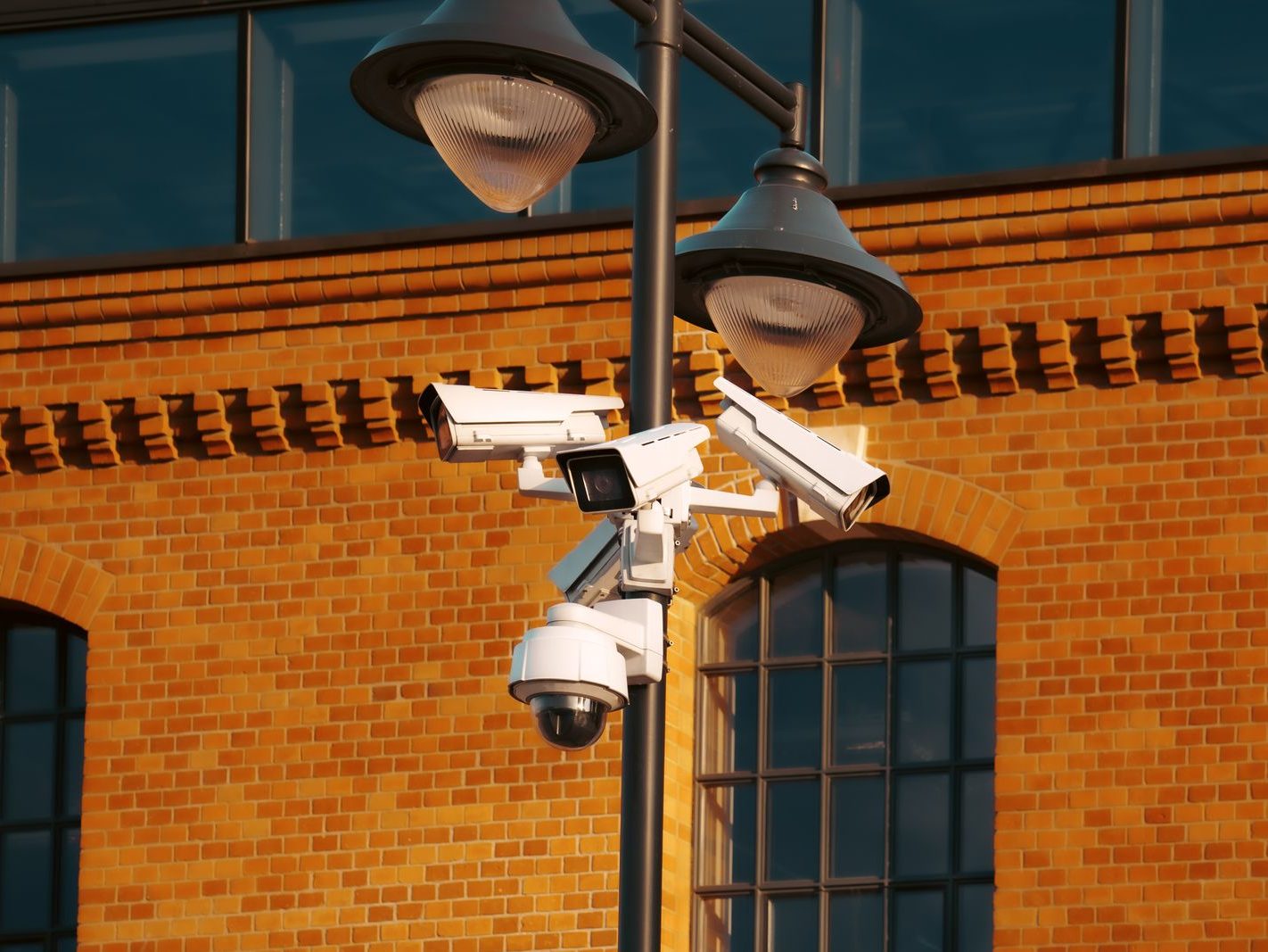 Security cameras mounted on a pole beside a brick building